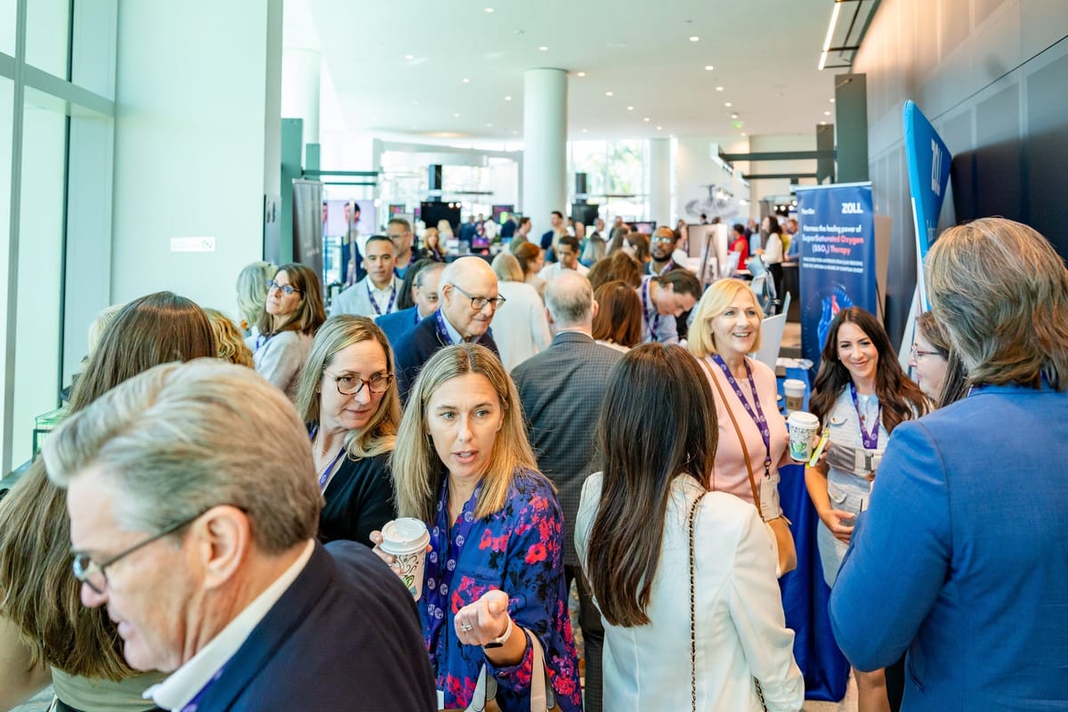 Busy cardiovascular summit exhibitor floor with attendees and sponsor displays