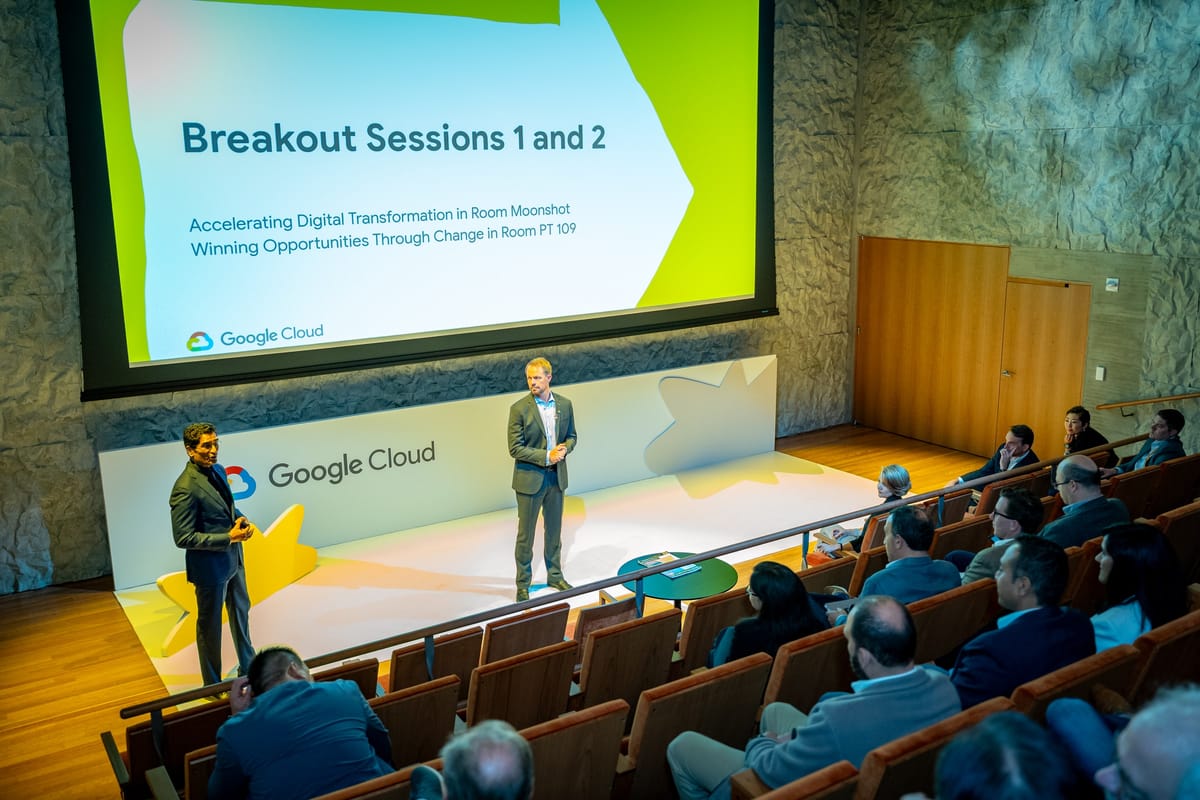 Google Cloud speakers leading a breakout session in an auditorium with the audience and branded stage visible