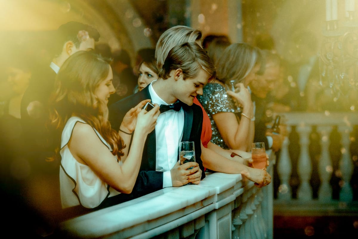 Guests in evening dress sharing a quiet moment along a museum gallery railing