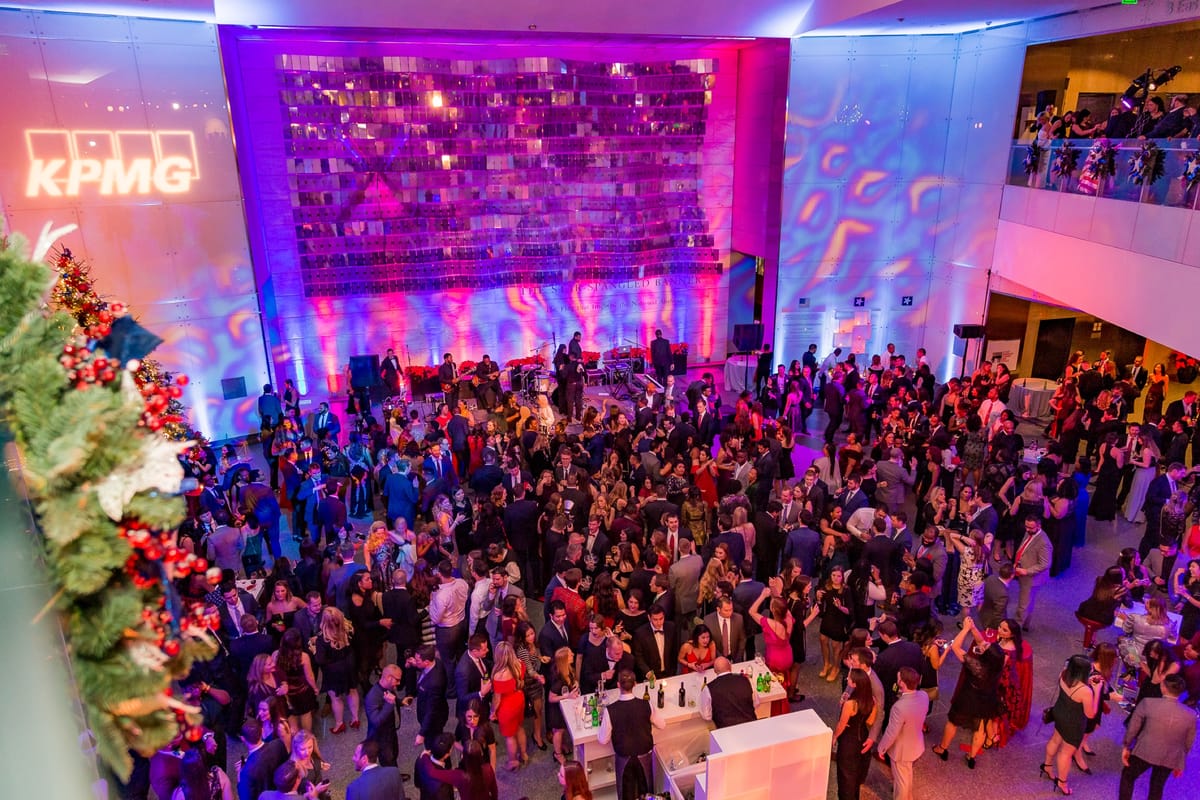 Large KPMG corporate celebration filling a museum atrium with magenta and blue event lighting