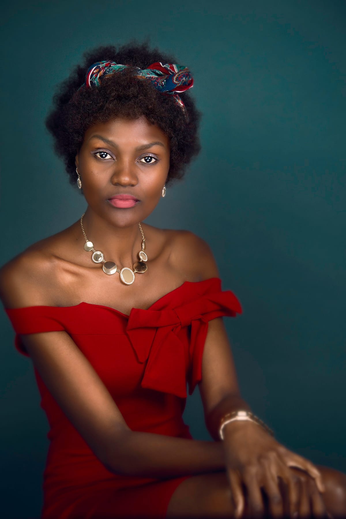 Editorial portrait of a woman in a red dress against a deep blue-grey background