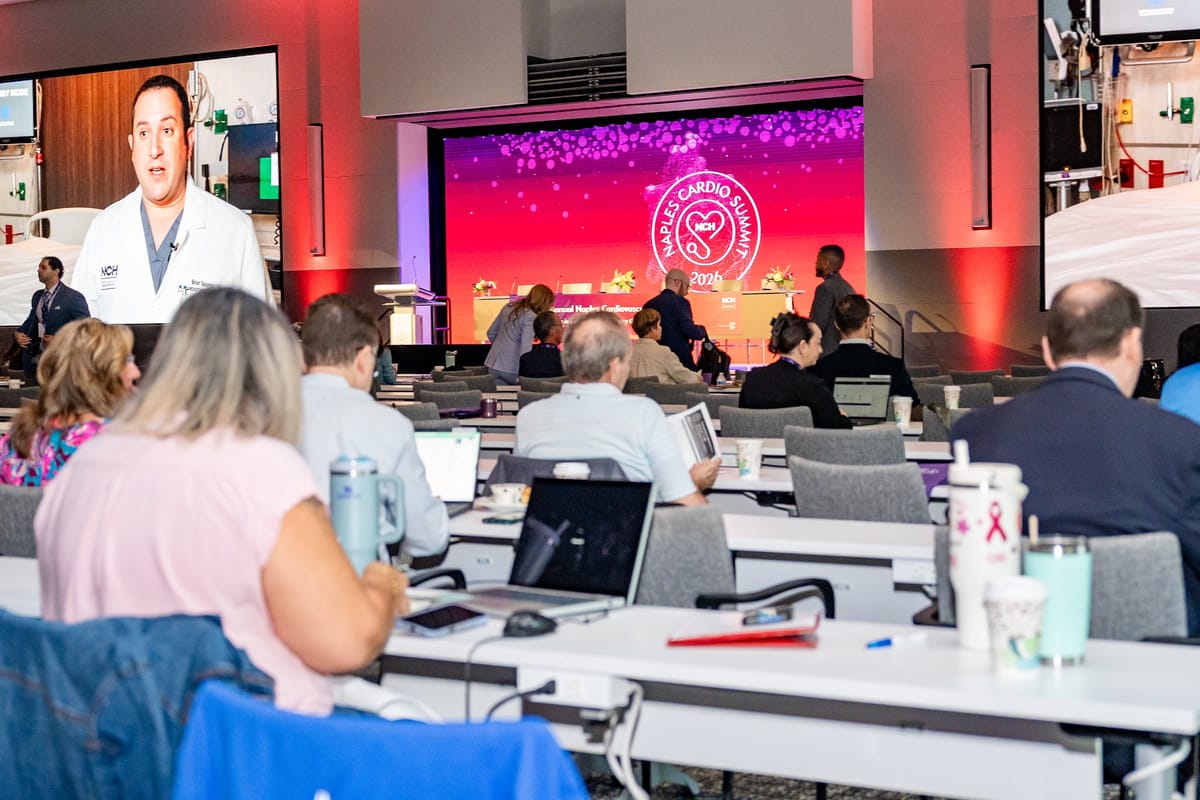 Physician presenting from the main stage with attendees listening in the foreground