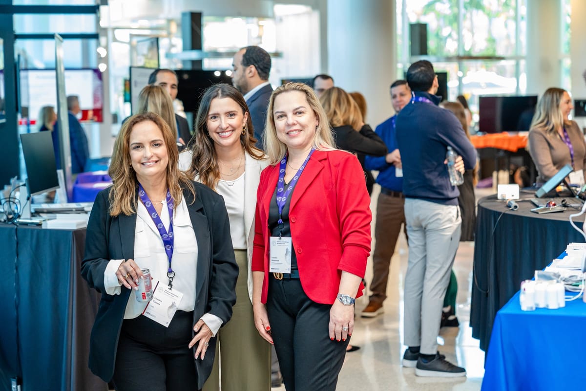 Three summit attendees photographed together on the active exhibitor floor